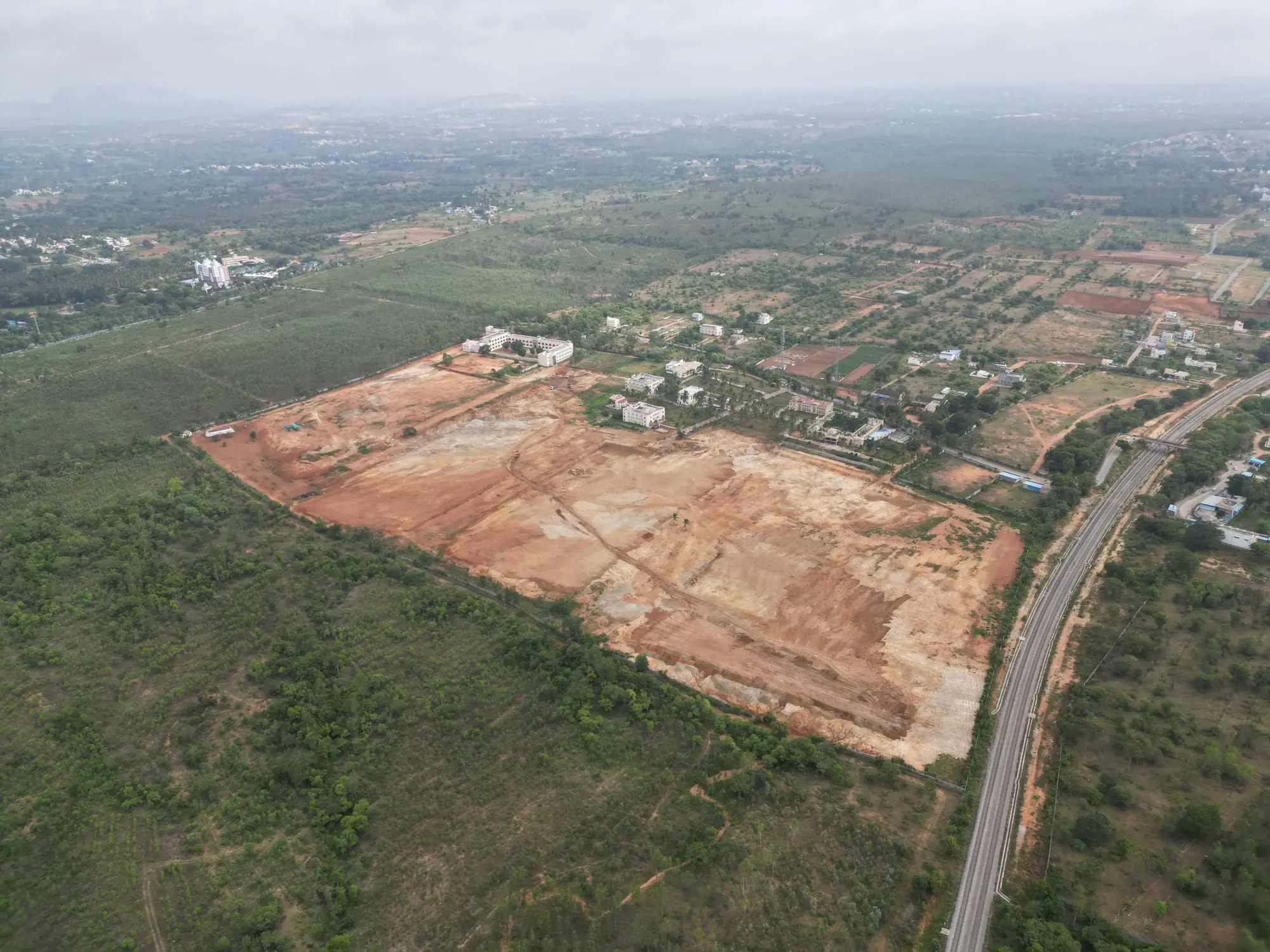 An excavator clearing a plot of brown earth for construction